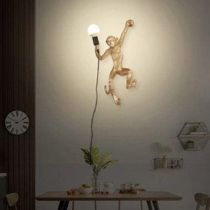 Gold resin monkey-shaped wall sconce holding a light bulb above a dining table